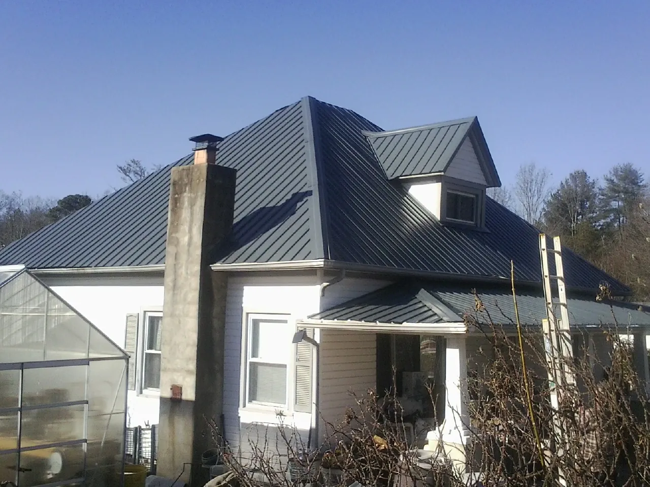 Dark blue standing seam metal roof on a white farmhouse with dormer — Slate & Tile Roof Repair by Roofing Brothers in Long Prairie