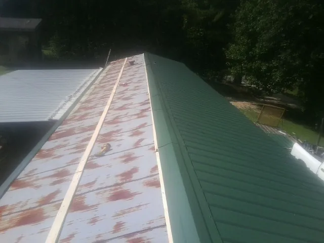 Old rusted panels beside newly installed green metal roofing — Wind Damage Roof Repair by Roofing Brothers in Long Prairie