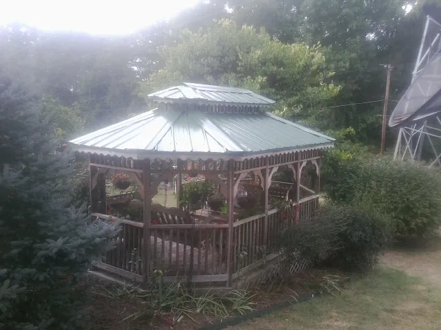 Green metal roof on a backyard gazebo surrounded by garden beds in Long Prairie