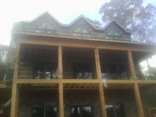 Dormers and porch framing on a large log home under construction — Roof Coating work by our crew in Long Prairie