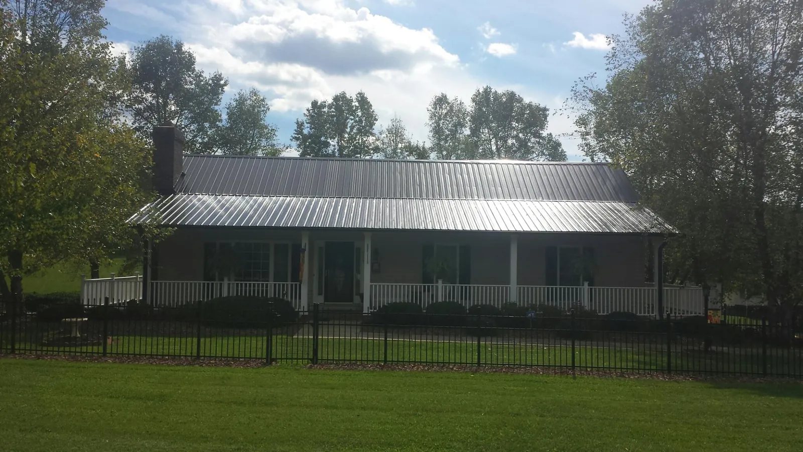Gray metal roof on a brick ranch with a full width front porch — Gutter Guard Installation work by our crew in Long Prairie
