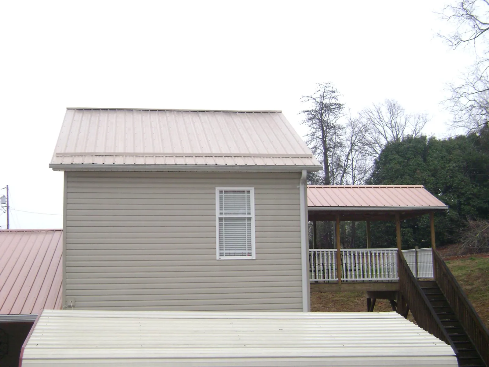 Tan metal roofs on a two story addition and attached porch, from a Roof Replacement job in Long Prairie