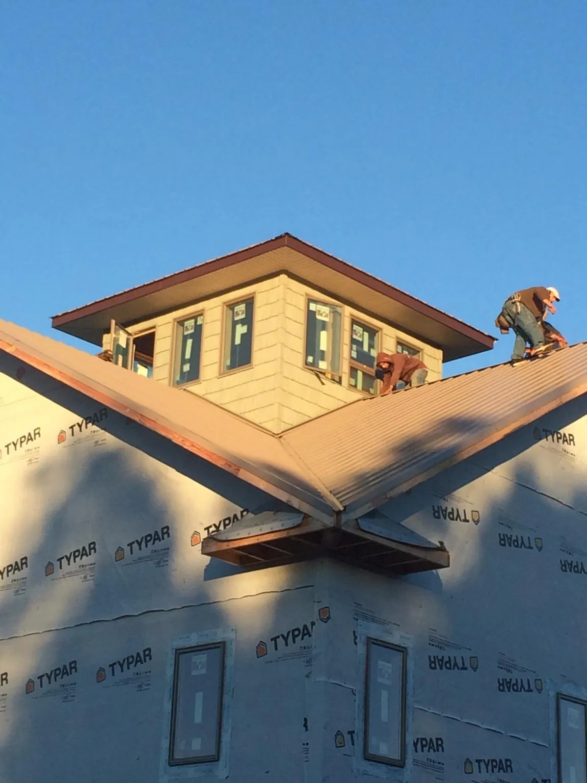 Roofers working around a rooftop cupola on a new metal roof at sunset — Roof Waterproofing in Long Prairie by Roofing Brothers